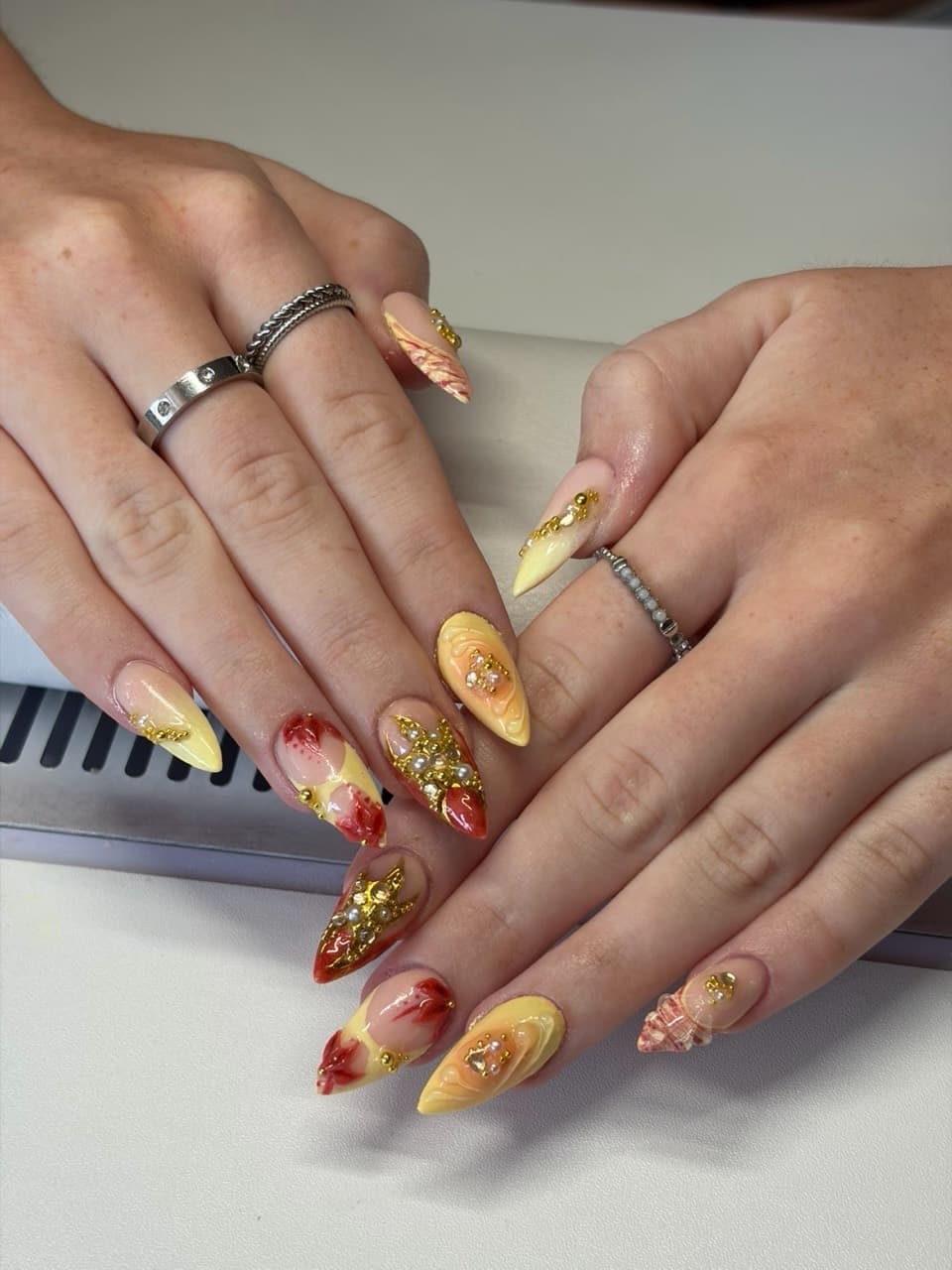 Gelbrote Nail Art mit goldenen Verzierungen